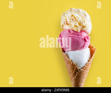 Coni da gelato multicolore su sfondo giallo estivo, delizioso concetto di gelato, estate calda Foto Stock