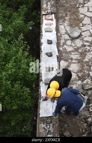 (240705) -- PECHINO, 5 luglio 2024 (Xinhua) -- i lavoratori coprono i mattoni appena posati con sacchi intrecciati per ripararsi dalla pioggia nella sezione Jiankou della grande Muraglia a Pechino, capitale della Cina, 2 luglio 2024. Quarant’anni fa, a Pechino è stata lanciata una campagna per proteggere la grande Muraglia con l’aiuto dei fondi sociali. Oggi le forze sociali svolgono ancora un ruolo cruciale nella protezione e nel restauro della grande Muraglia. Un progetto di restauro in corso della sezione Jiankou della grande Muraglia adotta un approccio "archeologia e restauro simultaneo", dove i lavori archeologici sono completati su una sezione B. Foto Stock