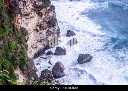 Una maestosa scogliera vicino all'oceano dove le onde si infrangono contro le rocce, a Uluwatu, Bali Foto Stock