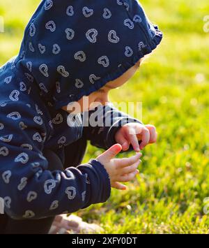 Piccola bambina gioca felice nel parco all'aperto in primavera e si raccoglie margherite. Foto Stock