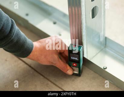 Mano che tiene un accurato misuratore laser sul pavimento. Foto Stock