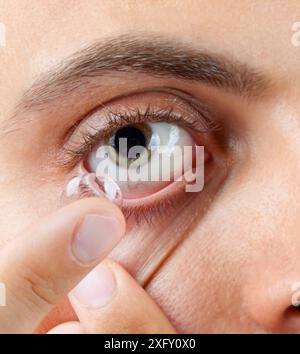 Primo piano di un uomo verde dell'occhio durante l'inserimento di un correttivo Foto Stock