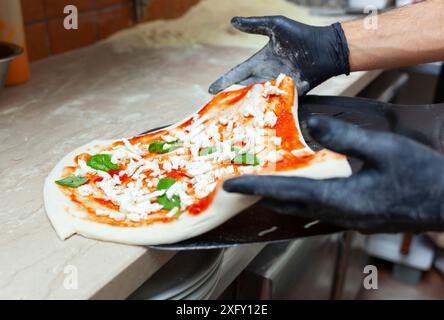 Materie pizza margherita messo sulla pala da forno per la cottura. Foto Stock