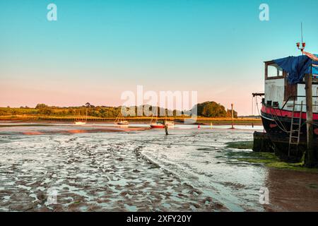 Tramonto sulle distese fangose durante la bassa marea vicino a una casa galleggiante ormeggiata a Woodbridge, Tide Mill Harbour, River Debden, Woodbridge, Suffolk, Inghilterra Regno Unito Foto Stock