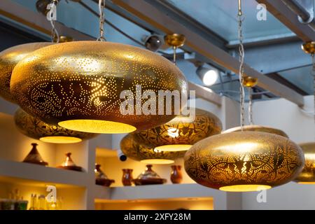 Una collezione di lampade dorate e bianche appese al soffitto. Gli apparecchi di illuminazione sono di varie forme e dimensioni, per creare un design unico e Foto Stock