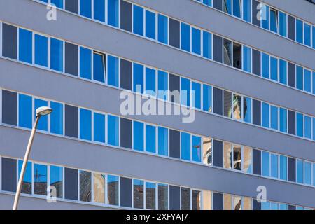 Il campanile della chiesa di San Nicola / San Nicola si riflette nelle finestre di vetro del moderno edificio vicino al Centro Congressi di Villach, Carinzia, Austria Foto Stock