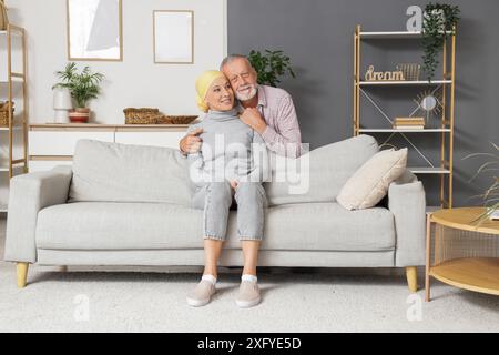 Uomo maturo che abbraccia sua moglie dopo la chemioterapia a casa Foto Stock