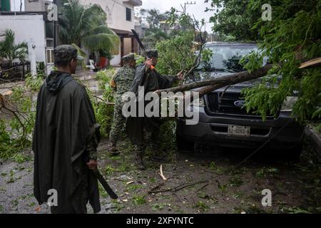 Tulum, Messico. 5 luglio 2024. I membri delle forze armate aiutano a rimuovere un albero caduto dopo il passaggio dell'uragano Beryl. I forti venti dell'uragano hanno rovesciato alberi, piloni elettrici e case coperte. Secondo il capo della difesa civile messicana Velazquez, il 50% del potere fu tagliato a Tulum, tra gli altri luoghi. Crediti: Felix Marquez/dpa/Alamy Live News Foto Stock