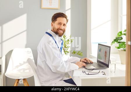 Giovane medico di sesso maschile fisioterapista seduto alla scrivania sul posto di lavoro in clinica medica Foto Stock