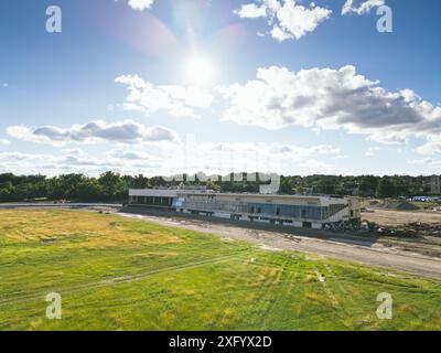 Un campo verde con un vecchio edificio vicino a un cantiere e macchinari Foto Stock