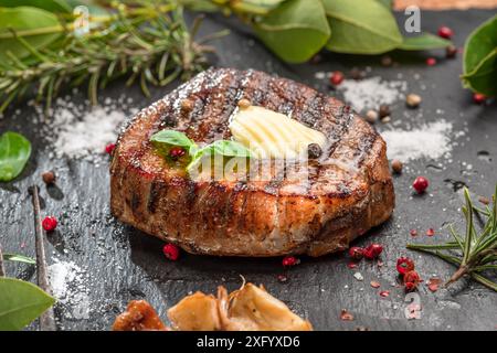 Deliziosa bistecca di riso grigliata con una fetta di burro. La bistecca viene servita su un piatto di ardesia nera. Foto Stock