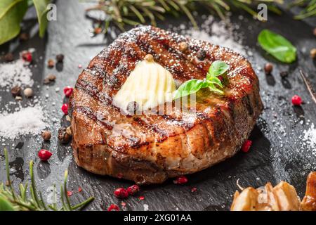 Deliziosa bistecca di riso grigliata con una fetta di burro. La bistecca viene servita su un piatto di ardesia nera. Posizione piatta. Foto Stock