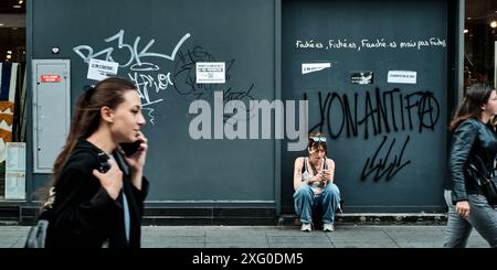 Lione, Francia. 14 giugno 2024. Liyanna, dal quartiere alternativo di sinistra di Croix Rousse, si trova di fronte a un negozio in Rue de la Republique sotto un graffito 'LYONANTIFA'. Domenica (7 luglio), sarà deciso come sarà l'Assemblea nazionale francese in futuro e chi potrebbe governare. Il Rassemblement National (RN) ha la prospettiva di assumere il governo in Francia. Crediti: Stefan Jaitner/dpa/Alamy Live News Foto Stock