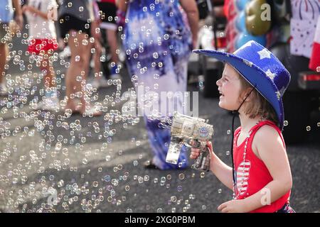 Sullivans Island, Stati Uniti d'America. 4 luglio 2024. Una giovane ragazza che indossa un costume usa una pistola a bolla durante l'annuale parata di biciclette e golf cart che celebra l'Independence Day il 4 luglio 2024 a Sullivans Island, Carolina del Sud. Crediti: Richard Ellis/Richard Ellis/Alamy Live News Foto Stock