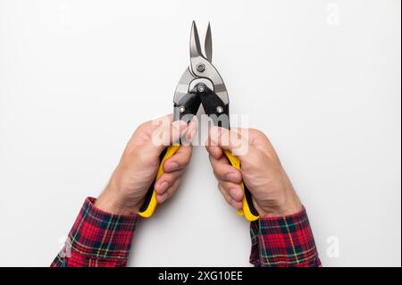 Le mani maschili tengono le pinze gialle luminose di un utensile da costruzione, su sfondo bianco. primo piano delle pinze Foto Stock