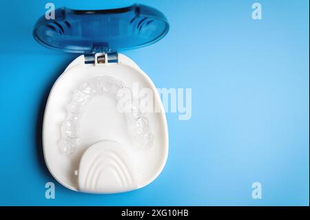 Le piastre in plastica invisibili si trovano in una speciale custodia ortodontica, una custodia bianca su sfondo blu Foto Stock