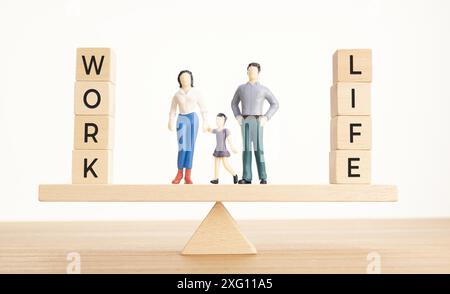 Equilibrio tra vita e concetto di lavoro. Figurine di famiglia e blocchi di legno con parola su Seesaw Foto Stock
