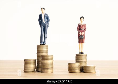 Concetto di differenza salariale tra uomini e donne. Uomo e donna in piedi sopra il mucchio di monete Foto Stock