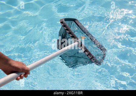 Uomo pulizia a mano di una piscina con rete Skimmer Foto Stock