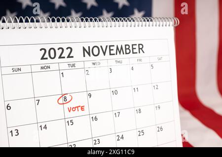 Novembre 2022 America Vote Day concetto. Calendario da tavolo con il 8 novembre contrassegnato in rosso e bandiera USA sullo sfondo Foto Stock