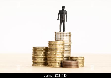 Ricchezza, fare soldi, concetto di crescita salariale. Figurina uomo d'affari in piedi su un mucchio di monete. Spazio di copia Foto Stock