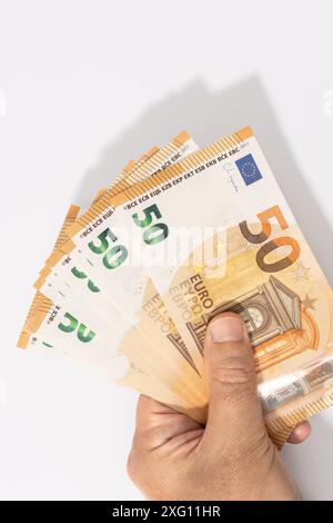 Mano che tiene un gruppo di 50 banconote in euro su sfondo bianco. Spazio di copia Foto Stock