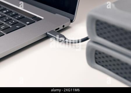Particolare del cavo esterno del disco rigido collegato a un moderno computer portatile sulla scrivania Foto Stock