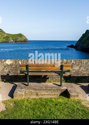 Panchina sulla spiaggia di Readymoney Cove con vista sul fiume Fowey verso Polruan, Cornovaglia, Inghilterra, Regno Unito Foto Stock