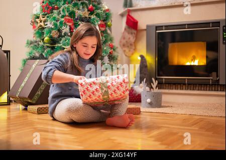 Bella ragazza che apre il regalo di natale. Fotografia di alta qualità Foto Stock