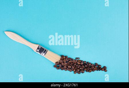 Dipingere con un pennello una linea con chicchi di caffè torrefatto, sfondo blu con spazio copia, bere una bevanda calda per la prima colazione, fare una pausa Foto Stock