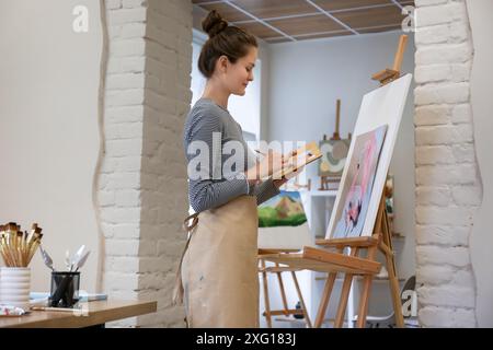 Donna che disegna su cavalletto con tela in studio Foto Stock