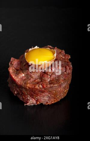 Tartare di bistecca su ardesia nera con un uovo Foto Stock