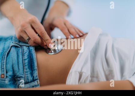 Gastroenterologo pediatrico che esegue l'esame addominale con stetoscopio. Foto Stock