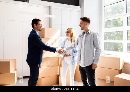 Coppia felice che festeggia l'accordo di chiusura con l'agente immobiliare in occasione della celebrazione del nuovo progetto aziendale di proprietà immobiliare Foto Stock