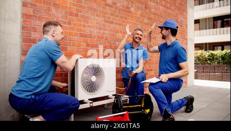 Un tecnico HVAC qualificato esegue la manutenzione, installa i condizionatori d'aria e segnala i risultati ai proprietari degli edifici in ambiente commerciale Foto Stock