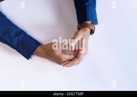 Primo piano di mani appoggiate sul tavolo, indossando camicia blu e orologio marrone, spazio copia Foto Stock