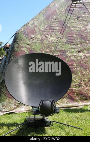 Antenna parabolica militare per ricevere segnali dai satelliti spia nello spazio nel campo durante la guerra e la tenda mimetica Foto Stock