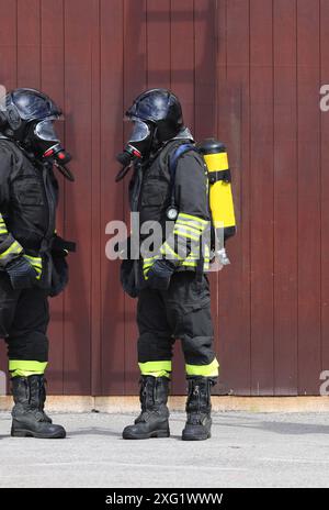 Due vigili del fuoco indossano maschere antigas e respiratori durante una risposta di emergenza. Foto Stock