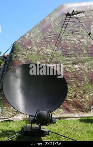 antenna militare parabolica per ricevere segnali dai satelliti spia nello spazio nel campo di soldati durante la guerra e camuffamento nel backgroun Foto Stock