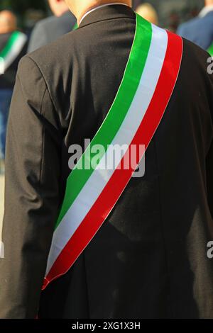 Elegante sindaco italiano in giacca nera e fascia tricolore della bandiera italiana durante la sfilata Foto Stock