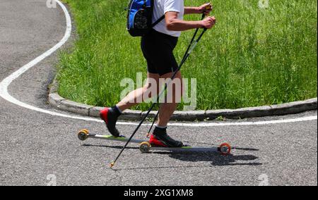 Sciatore con pista da sci su asfalto e pali per allenamento durante l'estate Foto Stock