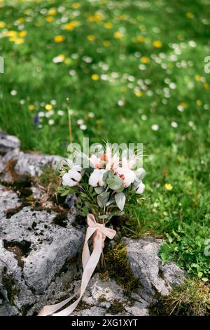 Un luminoso bouquet nuziale si staglia su pietre ricoperte di muschio su un prato verde Foto Stock