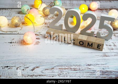 Benvenuto con 2025 lettere alfabetiche su sfondo in legno Foto Stock