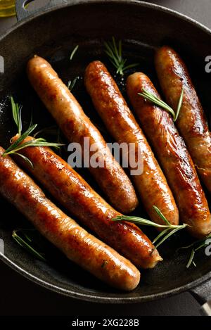 Salsicce sottili fritte in padella di ghisa. Vista ravvicinata Foto Stock