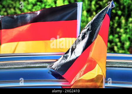 Deutschlandfahnen teils auf Halbmast, teils stolz im Wind flatternd, deutsche Stimmung nach dem Aus im Viertelfinale, München, 6. Juli 2024 Deutschland, München, 6. Juli 2024, der Morgen danach: Deutschlandfahnen am Auto teils auf Halbmsast, teils stolz im Wind wehend, deutsche Stimmung nach dem Ausscheiden beim Viertelfinale Deutschland-Spanien, traurig über das Aus, stolz auf die Leistung der Nationalmannschaft, UEFA EURO 2024, Fußball-Europameisterschaft, Sport, Fußball, Sport, *** bandiere tedesche in parte a mezz'asta, in parte svolazzanti con orgoglio nel vento, umore tedesco dopo l'eliminazione in acqua Foto Stock