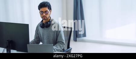 L'uomo asiatico ingegnere sollecito sviluppa un'applicazione di codifica con dati software seduti davanti al monitor del computer in ufficio Foto Stock