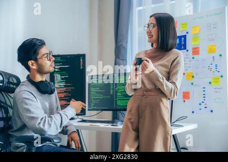 Due sviluppatori di software partecipano a una discussione durante la pausa caffè in un ufficio moderno, rilassano le emozioni Foto Stock