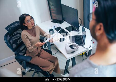 Discussione degli sviluppatori di software asiatici sul progetto di codifica sullo schermo del computer presso l'ufficio Moden Foto Stock