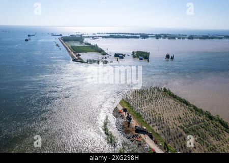 Hunan, Cina. 6 luglio 2024. (240706) -- YUEYANG, 6 luglio 2024 (Xinhua) -- una foto di un drone aereo scattata il 6 luglio 2024 mostra il sito di una breccia di diga nella città di Tuanzhou, nella contea di Huarong sotto la città di Yueyang, nella provincia di Hunan della Cina centrale. Secondo il Ministero della gestione delle emergenze, un team di lavoro è stato inviato nella provincia di Hunan della Cina centrale per guidare gli sforzi di salvataggio dopo una diga nel secondo lago d'acqua dolce più grande del paese il venerdì pomeriggio. Più di 800 persone del China National Comprehensive Fire and Rescue Team, 146 veicoli e 82 barche sono state inviate al Foto Stock