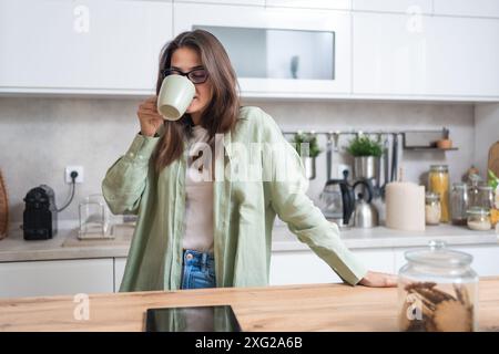 Vita semplice. Una giovane donna di routine mattutina nella cucina domestica del suo appartamento con il primo caffè per svegliarsi prima di andare al lavoro. Stile di vita di S. Foto Stock